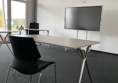 Schulungsraum mit Tisch, Stuhl und Samsung Flip digitaler Plipchart im Trainingscenter der Agora Akademie